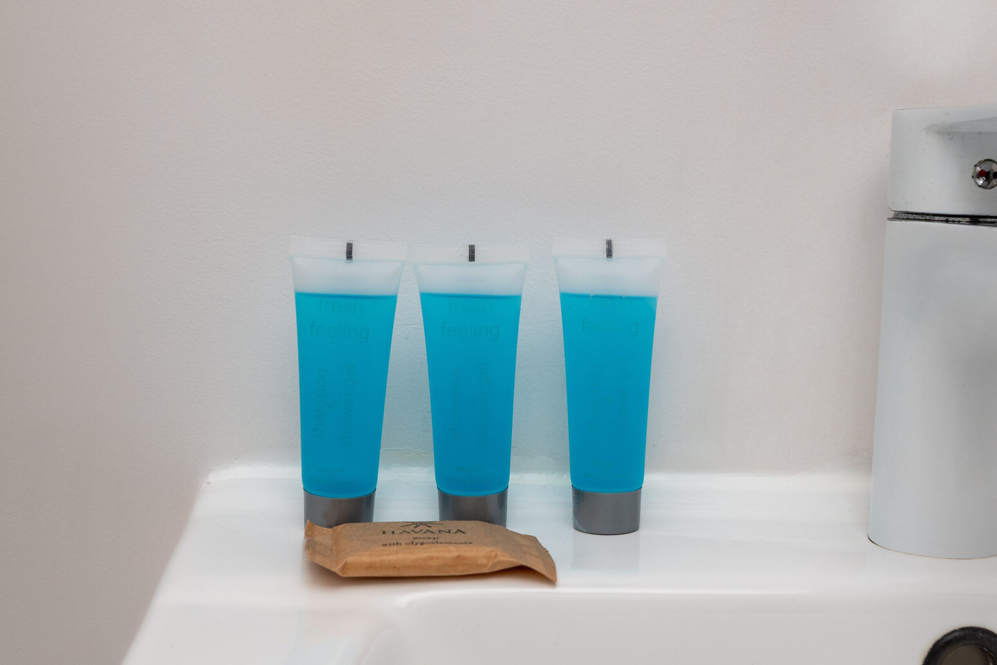 Three blue tubes on a white surface with a small brown packet beside them.