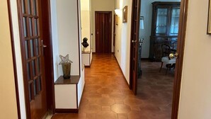 A hallway with a tiled floor, wooden doors, and a cabinet in the background. - Spacious, centrally located home, very close to the subway (Napoli)