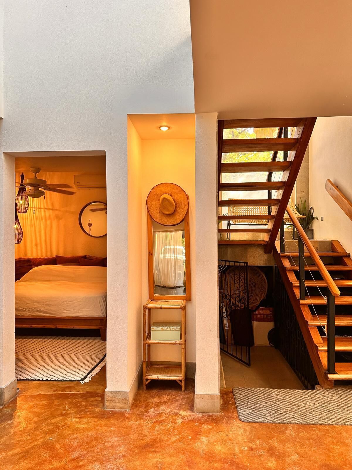 Ein kleines Hotelzimmer mit Bett, Tisch, Stuhl und einer Treppe.
