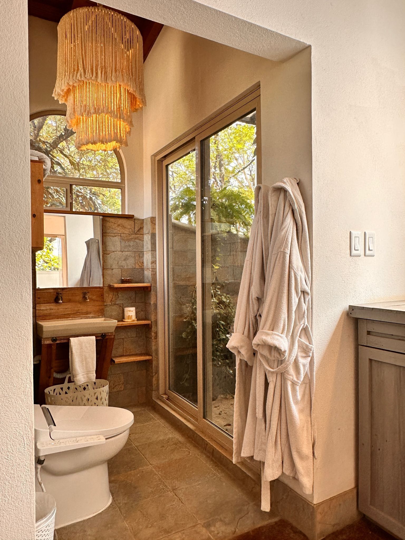 Une salle de bain avec des toilettes, un lavabo et une grande fenêtre.