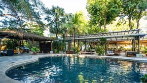 A swimming pool surrounded by lush greenery and outdoor seating areas. - Curiol Boutique Hotel & Lounge (Tempate)