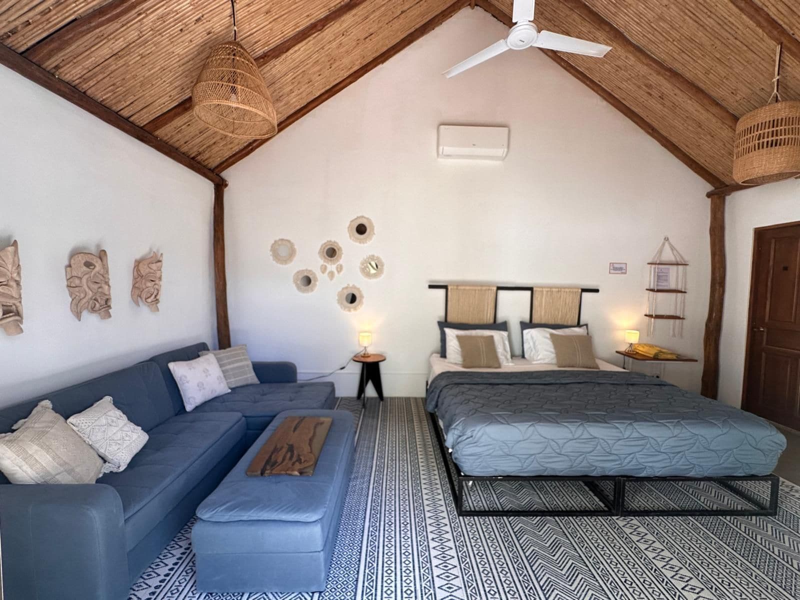 Une chambre à coucher comprenant un lit, un canapé, un ventilateur de plafond et des éléments de décoration murale.