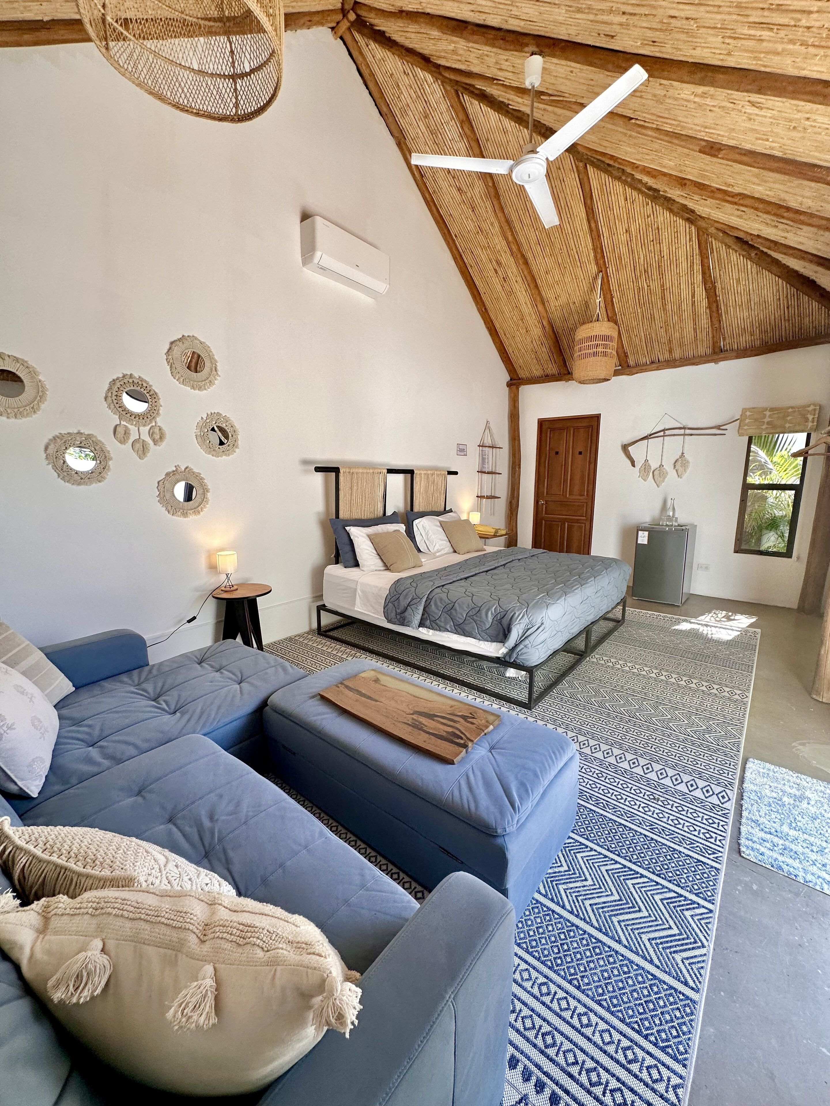 A bedroom with a bed, a sofa, a ceiling fan, and a patterned rug.
