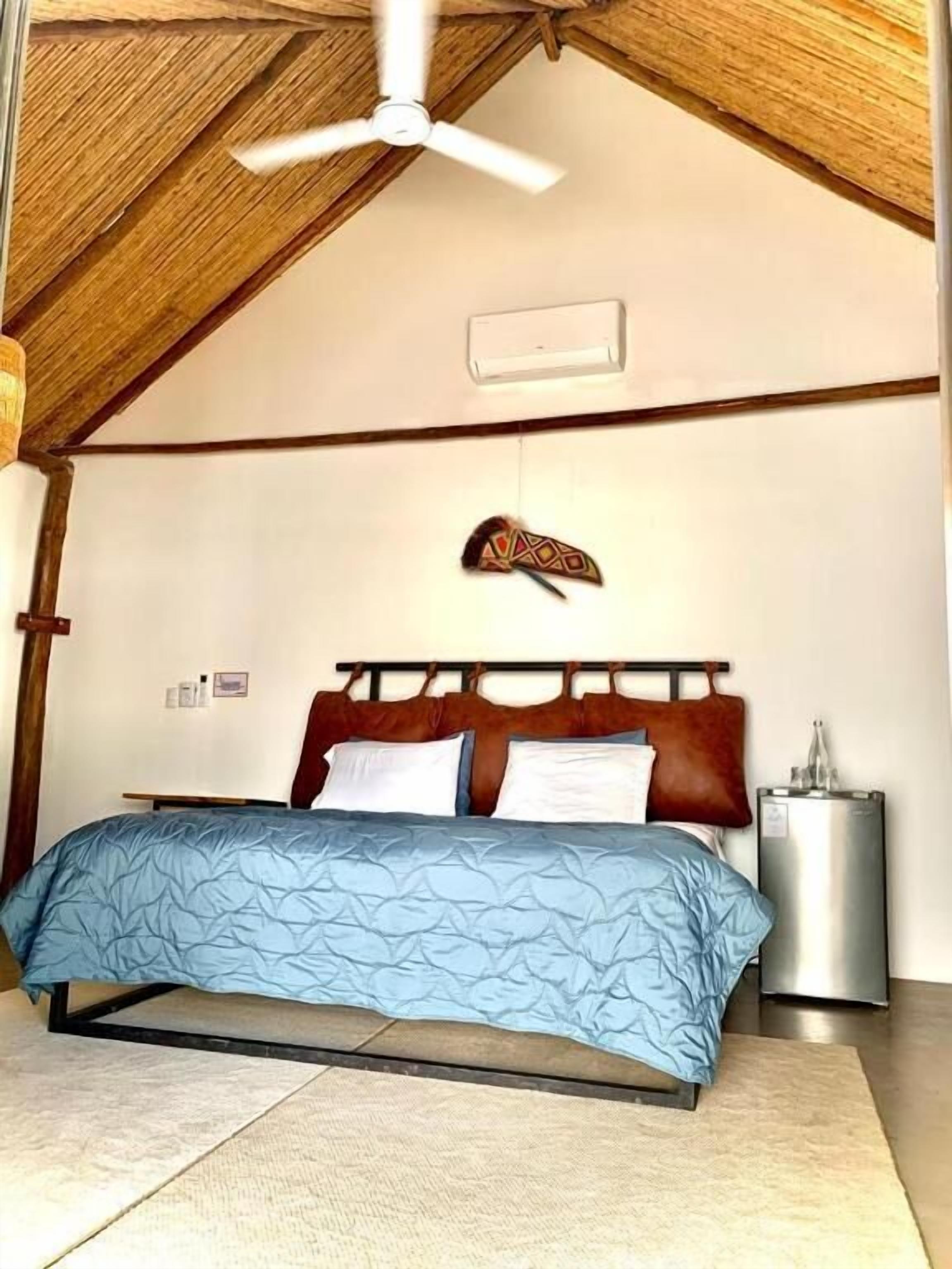 A bedroom with a bed, a ceiling fan, a decorative headboard, and a bedside table.
