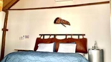 Una camera da letto con un letto, una ventola a soffitto, una testiera decorativa e un comodino.