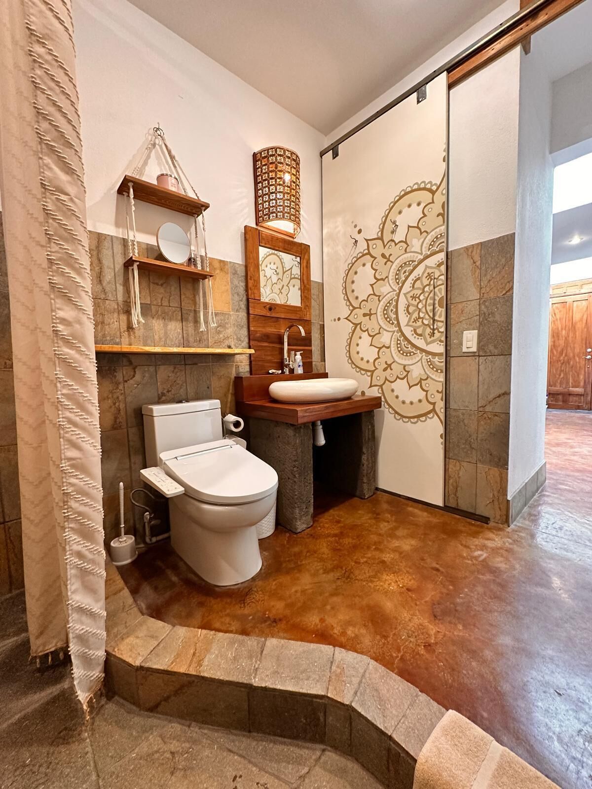A bathroom with a toilet, sink, and decorative wall.
