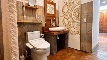 Un baño con inodoro, lavabo y un detalle decorativo en la pared.