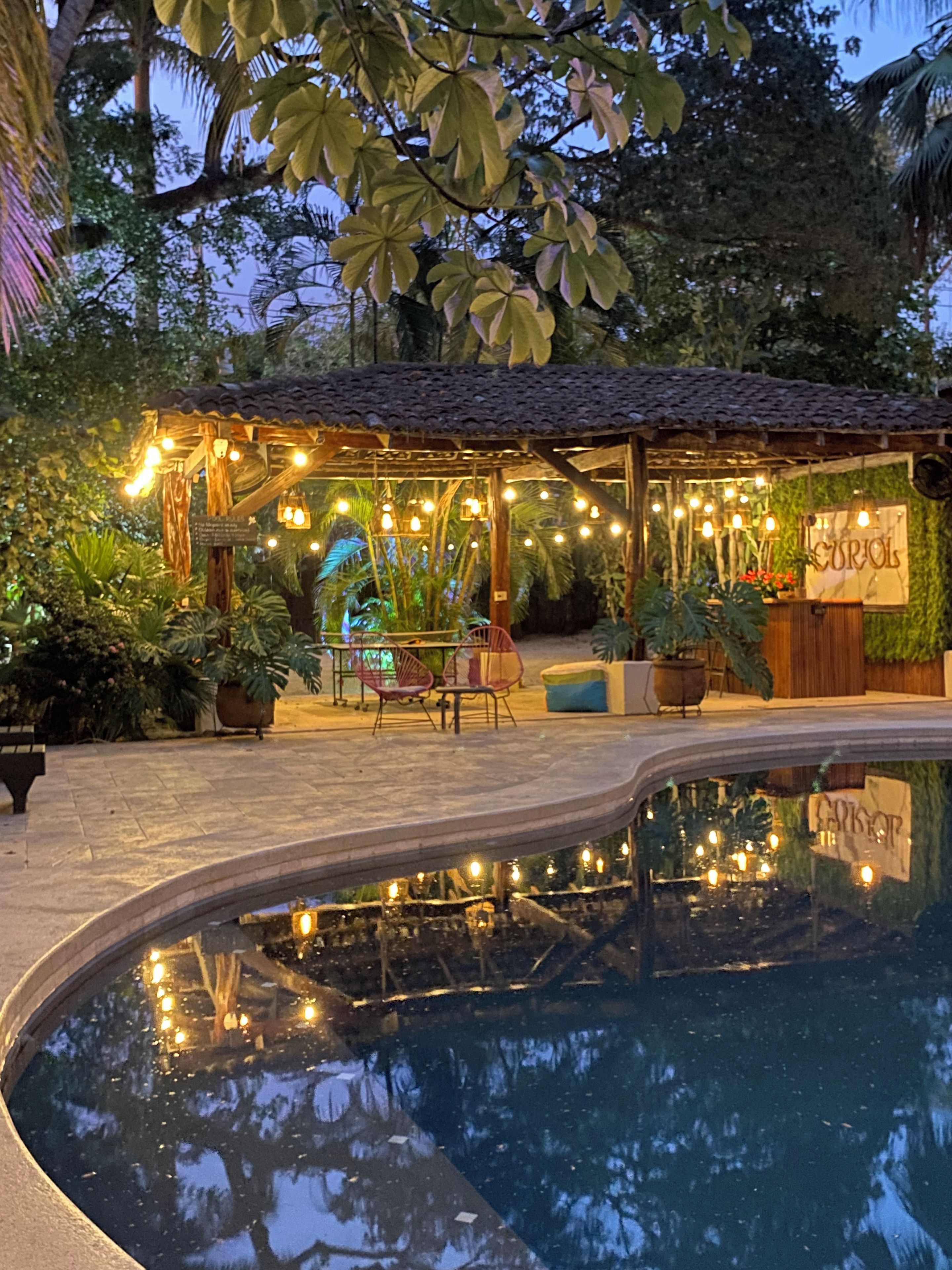 A pool area with a pergola, string lights, and seating.