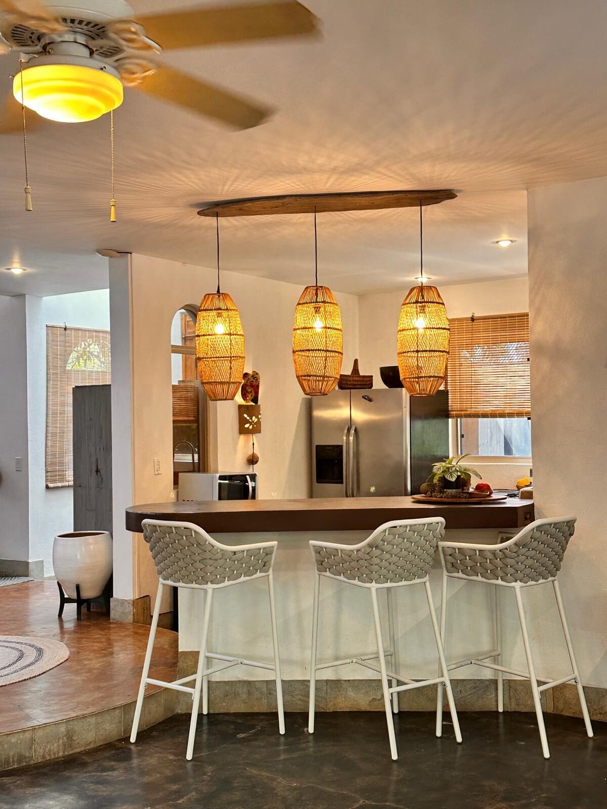 A modern kitchen with a central island, pendant lights, and a ceiling fan.