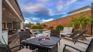 Eine Außenpatio mit einem Feuerkorb, Lounge-Stühlen und einem Pool.