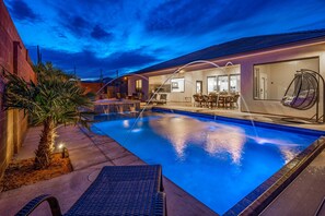 A swimming pool with a lounge area, a hanging chair, and a bar.