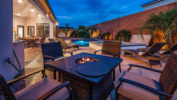 Eine Terrasse im Freien mit einem Feuerkorb, Liegestühlen und einem Swimmingpool.