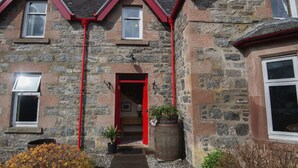 A stone building with a red entrance and multiple windows.
