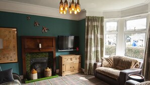 A cozy living room with a fireplace, a television, and a plaid carpet.