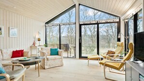 A spacious living area with a large glass door leading to a deck, wooden walls, and a comfortable seating arrangement. - Nice home in Ejstrupholm with kitchen (Ejstrupholm)