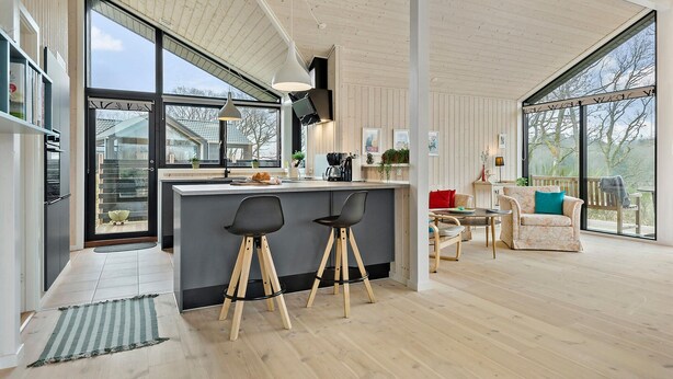 A modern kitchen with a large island, bar stools, and a dining area with a table and chairs. - Nice home in Ejstrupholm with kitchen (Ejstrupholm)