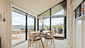A modern kitchen with a large window, wooden flooring, and a dining area with chairs and a table. - Nice home in Ejstrupholm with kitchen (Ejstrupholm)