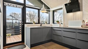A modern kitchen with grey cabinets, a black sink, and a large window overlooking a garden. - Nice home in Ejstrupholm with kitchen (Ejstrupholm)