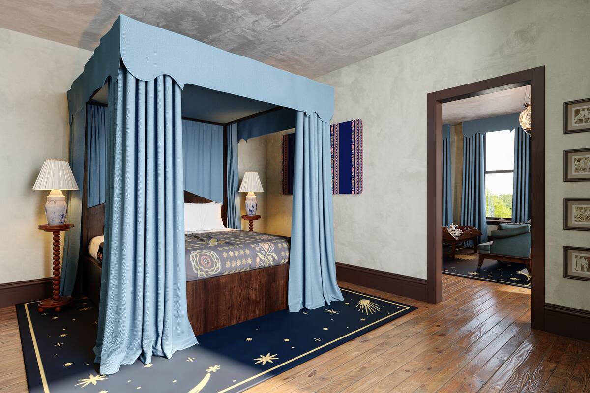 A four-poster canopy bed with a star-patterned rug, wooden flooring, and a view into an adjacent room with a table and chairs.