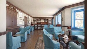 Una habitación amplia con zona de bar, diversas opciones de asientos y obras de arte enmarcadas en las paredes.