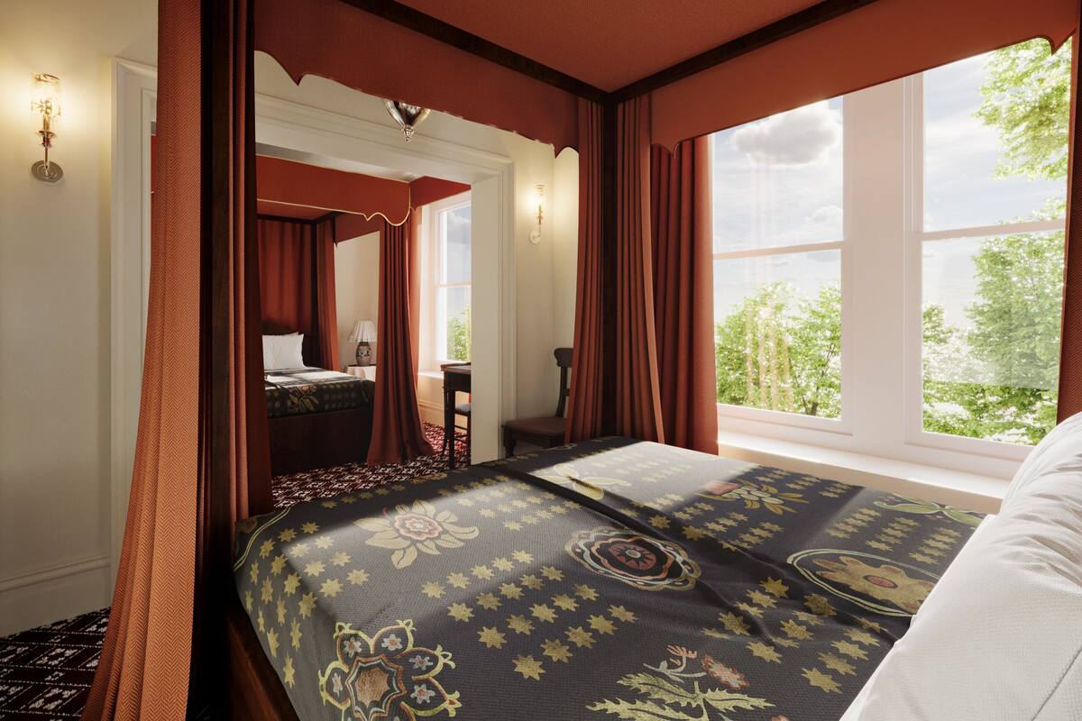 A hotel room with a large bed, a sitting area, and a window with a view of trees.