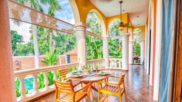 A covered outdoor dining area with a view of lush greenery, a brick wall, and a tiled floor. - Gorgeous Hacienda-style, private Casa de Paz, with 24-hour gated security (Bucerias)