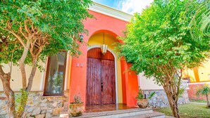 A building with a red facade, a wooden door, and steps leading to the entrance. - Gorgeous Hacienda-style, private Casa de Paz, with 24-hour gated security (Bucerias)