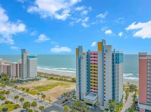 A coastal hotel with multiple high-rise buildings, a beach, and a clear blue sky.