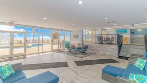 En hotellobby med utsikt över poolen, utomhusmöbler och en trappa.