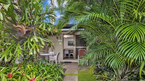 A tropical garden with a pathway leading to a building with a 'Relax' sign, surrounded by lush greenery and ferns. - Balgal Beach Units (Balgal Beach)