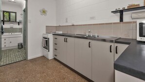 A modern kitchen with white cabinets, a black countertop, and an LG microwave. - Balgal Beach Units (Balgal Beach)