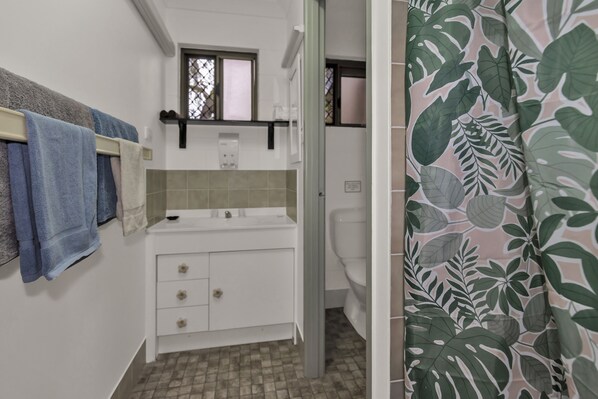 A bathroom with a white sink, a mirror, and a towel rack with blue towels. - Balgal Beach Units (Balgal Beach)