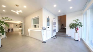 A modern hotel reception area with a clean, minimalist design, a reception desk, a digital information board, and a staircase leading to the upper floors. - JI STAY Hotel Gyeongju (Gyeongju)