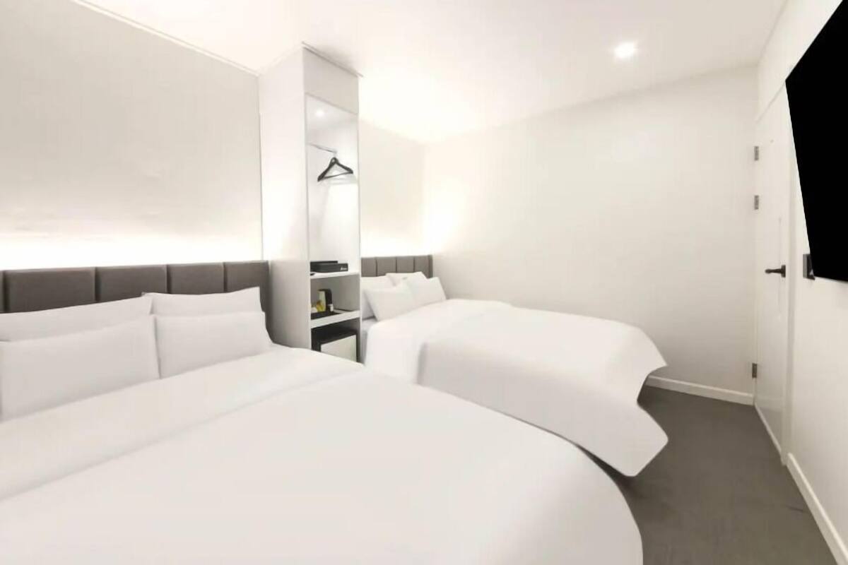 Ein modernes Hotelzimmer mit zwei Betten, einem Nachttisch und einem Kleiderschrank.