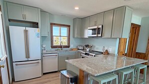 A kitchen with a central island, stainless steel appliances, and light-colored cabinetry. - Edgewater - Oceanfront with panoramic views! 4 bedroom, 3 baths, dog friendly and spa bath! (Southern Shores)