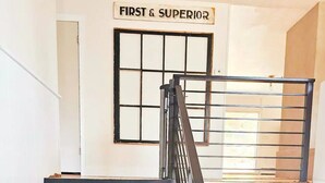 Un escalier dont les marches alternent entre le noir et le beige, une rampe en métal et une enseigne au-dessus indiquant « PREMIER ET SUPÉRIEUR ».