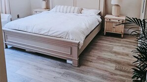 Une chambre avec un grand lit, un ventilateur de plafond, des lampes de chevet et une fenêtre.