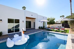 A modern house with a swimming pool, outdoor seating, and a swan float.