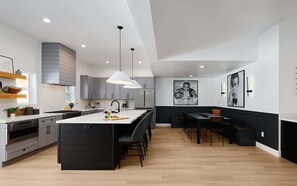A modern kitchen with a central island, pendant lighting, and a dining area with a bench. - Monroe-Private Pool-Ping Pong-North Scottsdale (Scottsdale)