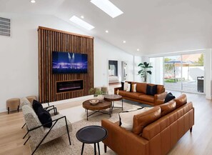 A modern living room with a flat-screen TV, leather sofas, a coffee table, and a fireplace. - Monroe-Private Pool-Ping Pong-North Scottsdale (Scottsdale)