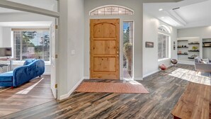 Un pasillo amplio con puerta de madera, un sofá azul y una zona de comedor con alfombra.