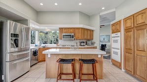 Una cocina moderna con electrodomésticos de acero inoxidable, armarios de madera y una isla grande con taburetes de bar.
