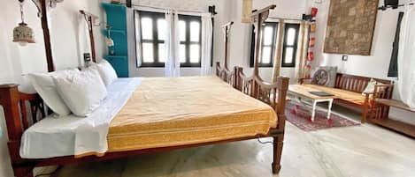 A spacious bedroom with a large bed, wooden furniture, and multiple windows.