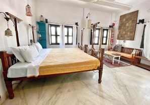 A spacious bedroom with a large bed, wooden furniture, and multiple windows.