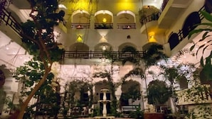 Un atrium intérieur doté d’une fontaine centrale, de nombreux balcons et d’une végétation luxuriante.