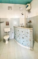 Un baño con inodoro blanco, ducha con pared decorada y calentador de agua instalado en el techo.