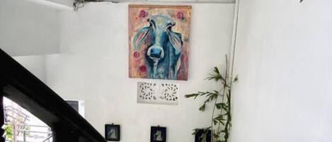 A staircase with white walls, a blue cow painting, and a small decorative item on the wall.