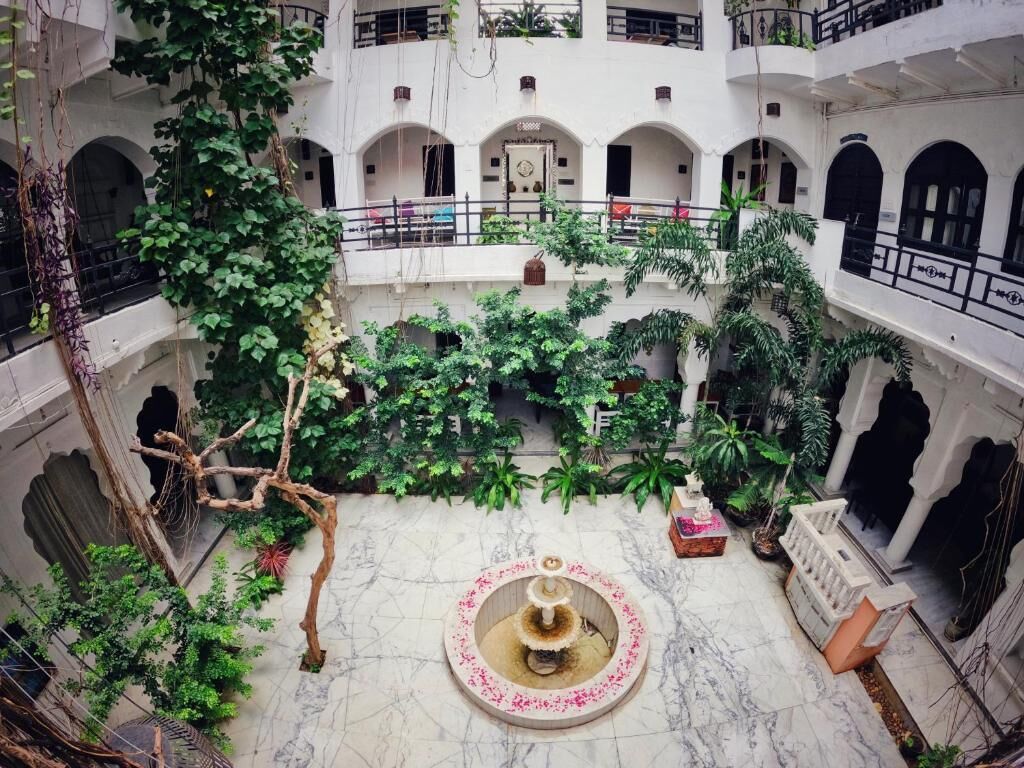 A courtyard with a central fountain, surrounded by lush greenery and multiple balconies.
