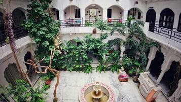 A courtyard with a central fountain, surrounded by lush greenery and multiple balconies.