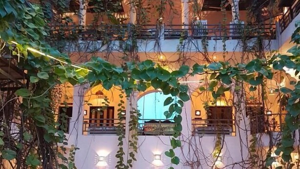 Un immeuble à plusieurs étages doté de balcons, d’arcades et de guirlandes lumineuses.